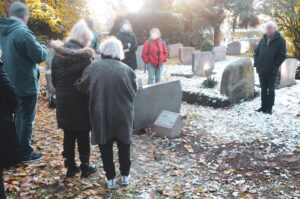 Querformat Foto von Menschen, die bei Schnee und Frost auf einem Friedhof stehen