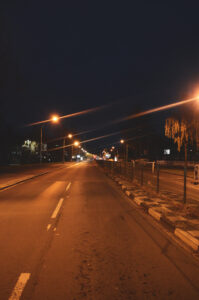 Hochkant Foto einer vierspurige Straße in der Nacht in orangefarbenem Straßenlaternenlicht.